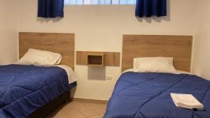 a bedroom with two beds with blue sheets and a window at La Pascana Hospedaje in Cajamarca