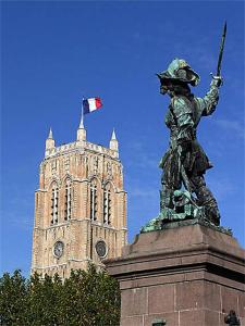 une statue devant une tour avec drapeau dans l'établissement Appartement Dunkerque, à Dunkerque