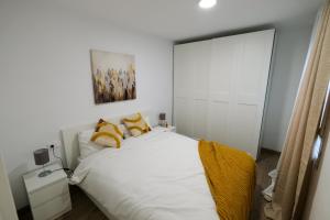 um quarto com uma cama branca e almofadas amarelas em 2B PlusUltra piso de 1 dorm em Alicante