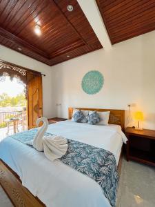 a bedroom with two beds with a swan on the bed at Nano Ari Homestay in Ubud
