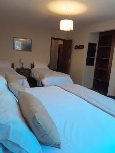 a hotel room with three beds and a light at Hotel Las Cascadas in La Cumbrecita