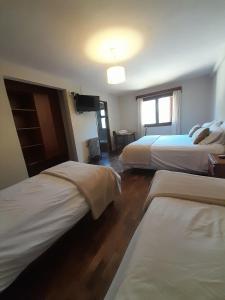 a hotel room with two beds and a television at Hotel Las Cascadas in La Cumbrecita