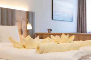 un letto con lenzuola bianche e cuscini sopra di Appartement Krippenstein mit Indoorpool und Sauna a Bad Goisern Altre 22 foto