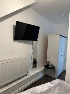 a flat screen tv hanging on the wall of a bedroom at Willesden J Guest Home 4 in London