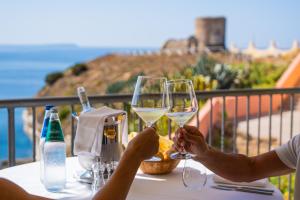 dwoje ludzi trzymających kieliszki białego wina na stole w obiekcie Hotel La Baja w mieście Santa Caterina