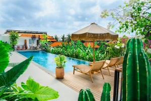 an outdoor deck with chairs and an umbrella and a swimming pool at KARRA LOFT - Bali Invest Villas in Canggu