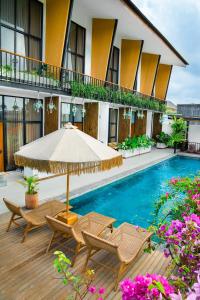 a patio with chairs and an umbrella and a swimming pool at KARRA LOFT - Bali Invest Villas in Canggu