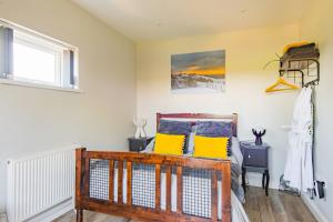 1 dormitorio con cama de madera y almohadas amarillas en Channel View by Bloom Stays, en Folkestone