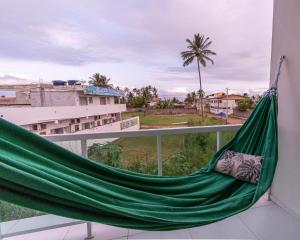 a hammock on a balcony with a view of a city at Melhor Localização com Varanda, Cozinha, Estacionamento e Home Office a 100M praia Barra Grande/Maragogi in Maragogi