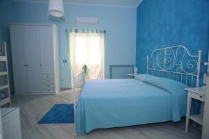 a blue bedroom with a bed and a window at Le Nereidi BeB in Margherita di Savoia