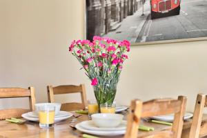 einen Tisch mit einer Vase rosa Blumen drauf in der Unterkunft Tyzenhauz Apartments Lobzowska Street in Krakau