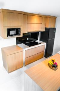 a kitchen with wooden cabinets and a black refrigerator at KAMMARA LOFT - Bali Invest Club in Canggu +3 photos