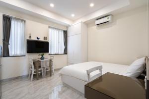 a bedroom with a bed and a table and a tv at F-APARTMENT in Ho Chi Minh City
