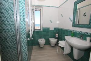 y baño con 2 aseos, lavamanos y espejo. en Le Nereidi BeB, en Margherita di Savoia