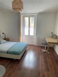 een slaapkamer met een bed, een bureau en een raam bij La Maison de Guilaine in Vichy