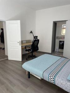 een kamer met een bed, een bureau en een stoel bij La Maison de Guilaine in Vichy