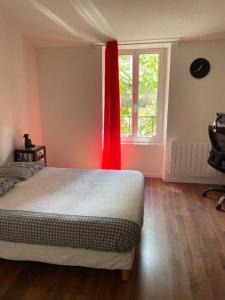 een slaapkamer met een bed met een rood gordijn en een raam bij La Maison de Guilaine in Vichy