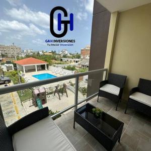 einen Balkon mit Stühlen und Poolblick in der Unterkunft Apartamento Con piscina cerca de la playa in La Romana
