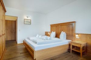 um quarto com uma grande cama branca e uma cabeceira em madeira em Appartement Predigstuhlblick mit Indoorpool und Sauna em Bad Goisern