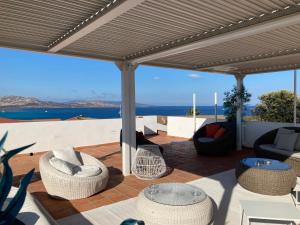 un patio con sillas y mesas y vistas al océano en Cala Rosa Club Hotel en Stintino