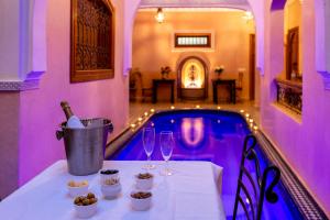 a table with wine glasses and a swimming pool at Riad Arbre Bleu in Marrakech