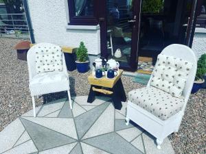 two chairs and a table in front of a house at The Hive at Seonaidbheag in Perth