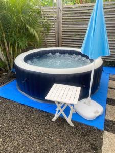 a hot tub with a chair and an umbrella at PAVILLON TI GEMME LE DIAMANT in Le Diamant