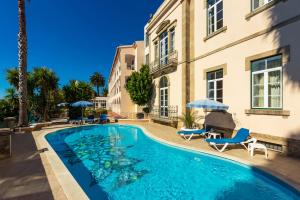 einen Pool mit Stühlen und Sonnenschirmen neben einem Gebäude in der Unterkunft Hotel Sol e Serra in Castelo de Vide