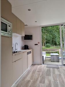 a kitchen with white cabinets and a large window at Tiny house aan het Zuidlaardermeer - vlakbij Groningen in Kropswolde