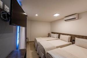 a room with two beds and a flat screen tv at Hotel Mais1 in Campina Grande