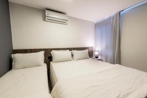 two beds in a hotel room with white sheets at Hotel Mais1 in Campina Grande