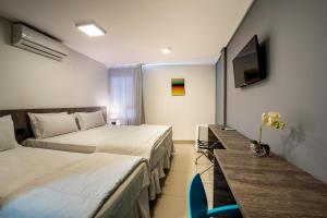 a hotel room with two beds and a television at Hotel Mais1 in Campina Grande