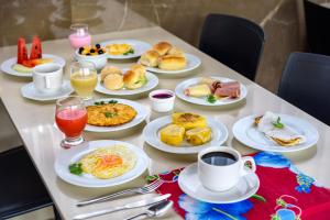 a table with plates of food and cups of coffee at Hotel Mais1 in Campina Grande