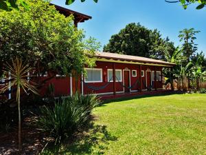 uma casa vermelha com um relvado verde em frente em Pousada Sertão em Alto Paraíso de Goiás