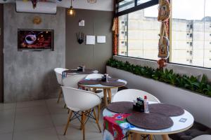 a restaurant with two tables and white chairs at Hotel Mais1 in Campina Grande