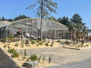un grand bâtiment en verre avec des gens à l'intérieur dans l'établissement Cottage dans Parc Résidentiel de Loisirs, Piscine, 150M de la mer, à Jullouville 18 autres photos