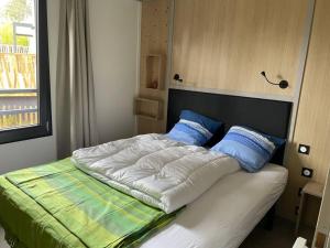 un lit avec deux oreillers bleus dessus dans l'établissement Cottage dans Parc Résidentiel de Loisirs, Piscine, 150M de la mer, à Jullouville