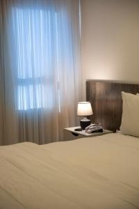 a bedroom with a bed with a lamp and a window at Hotel Mais1 in Campina Grande