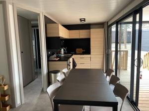 une salle à manger avec une table et des chaises et une cuisine dans l'établissement Cottage dans Parc Résidentiel de Loisirs, Piscine, 150M de la mer, à Jullouville