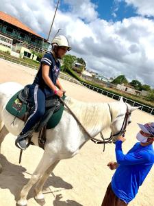 una mujer montando en un caballo blanco con un palo de polo en Flat 808 Villa Hípica, en Gravatá