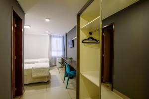 a room with a mirror and a bed and a desk at Hotel Mais1 in Campina Grande