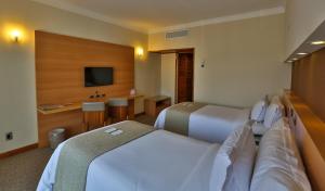 a hotel room with two beds and a television at Bourbon Santos Convention Hotel in Santos