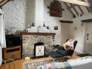 a living room with a stone fireplace and a tv at The Dairy @ Trefechan Wen in Goodwick