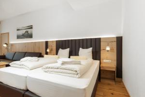 a bedroom with two white beds and a couch at Appartementhaus Dachsteinblick mit Indoorpool und Sauna in Bad Goisern
