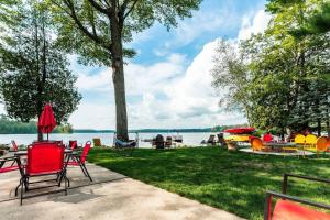 una mesa de picnic y sillas en el césped junto a un lago en Big Blue Lake Cottages, LLC - Cottage #2, en Holton