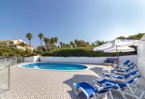 a swimming pool with lounge chairs and an umbrella and a pool at Casa Pachorrenta in Carvoeiro