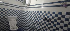 a bathroom with a toilet and black and white tiles at MERCY INN in Chennai