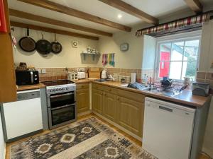 a kitchen with wooden cabinets and a stove top oven at The Dairy @ Trefechan Wen in Goodwick