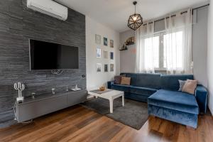 uma sala de estar com um sofá azul e uma televisão em La casa di Vittoria em Arona