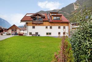 duży dom z zielonym trawnikiem przed nim w obiekcie Apartement Bens Auszeit Top 5 w mieście Umhausen